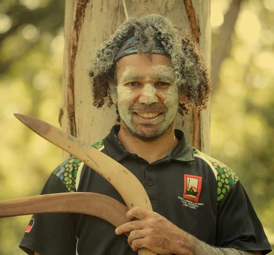 Aboriginal man in paint with boomerangs